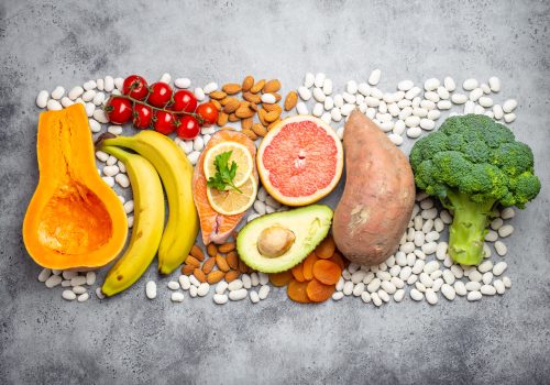 Vegetables, fruit and foods containing potassium over gray stone background, top view. Natural sources of potassium, vitamins and micronutrients for healthy balanced diet and avitaminosis prevention